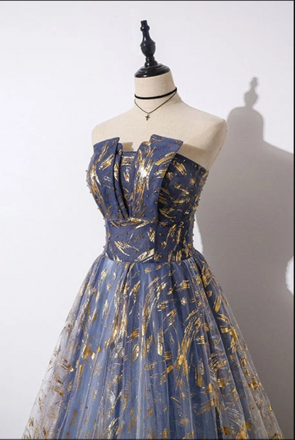 Blue evening gown with gold patterns on a mannequin against a white background